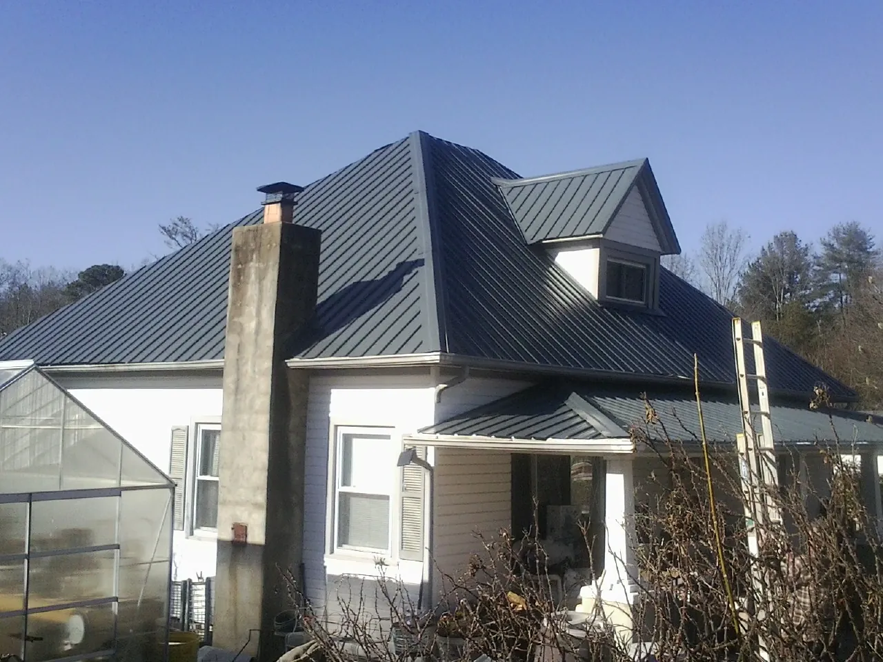 Dark blue standing seam metal roof on a white farmhouse with dormer — Slate & Tile Roof Repair by Roofing Brothers in Northboro