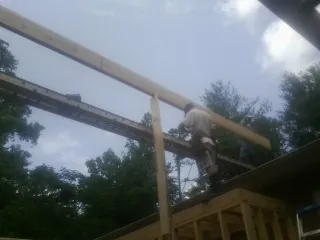 Carpenter setting a ridge beam over a new addition frame — Ice Dam Removal by Roofing Brothers in Northboro