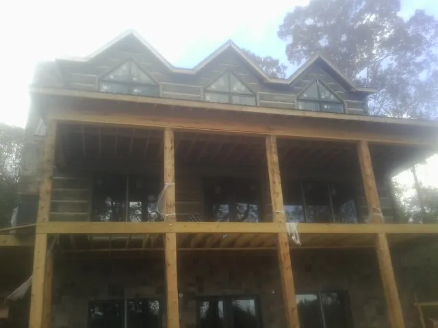 Dormers and porch framing on a large log home under construction — Roof Coating work by our crew in Northboro