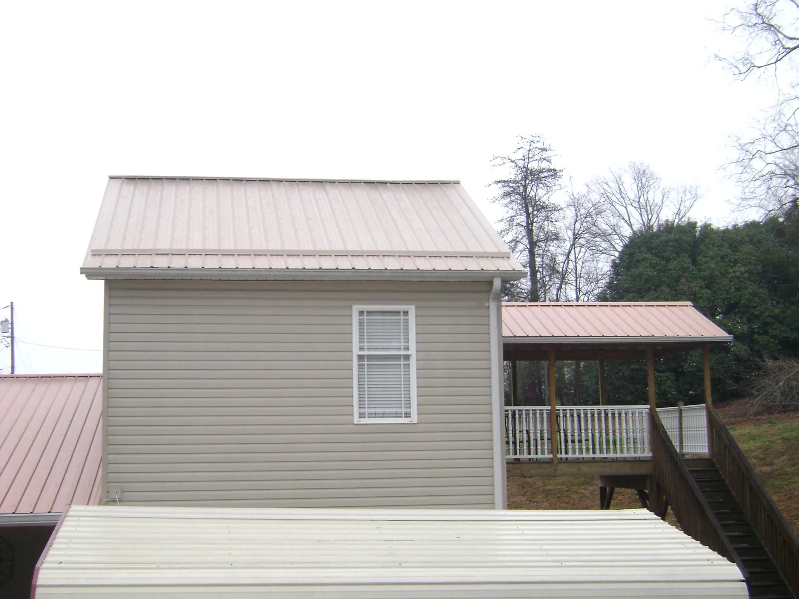 Tan metal roofs on a two story addition and attached porch, from a Roof Replacement job in Northboro