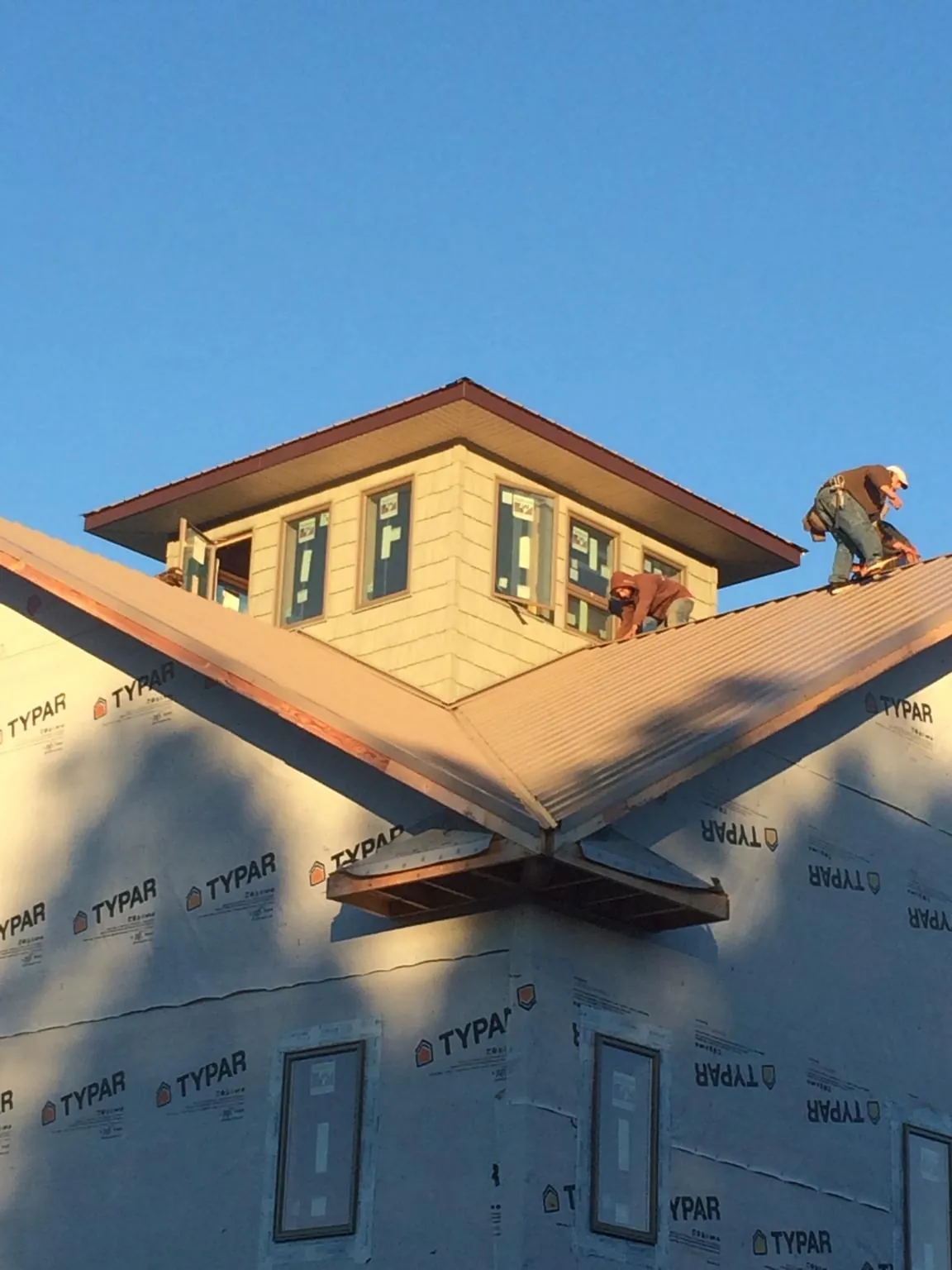 Roofers working around a rooftop cupola on a new metal roof at sunset — Roof Waterproofing in Northboro by Roofing Brothers